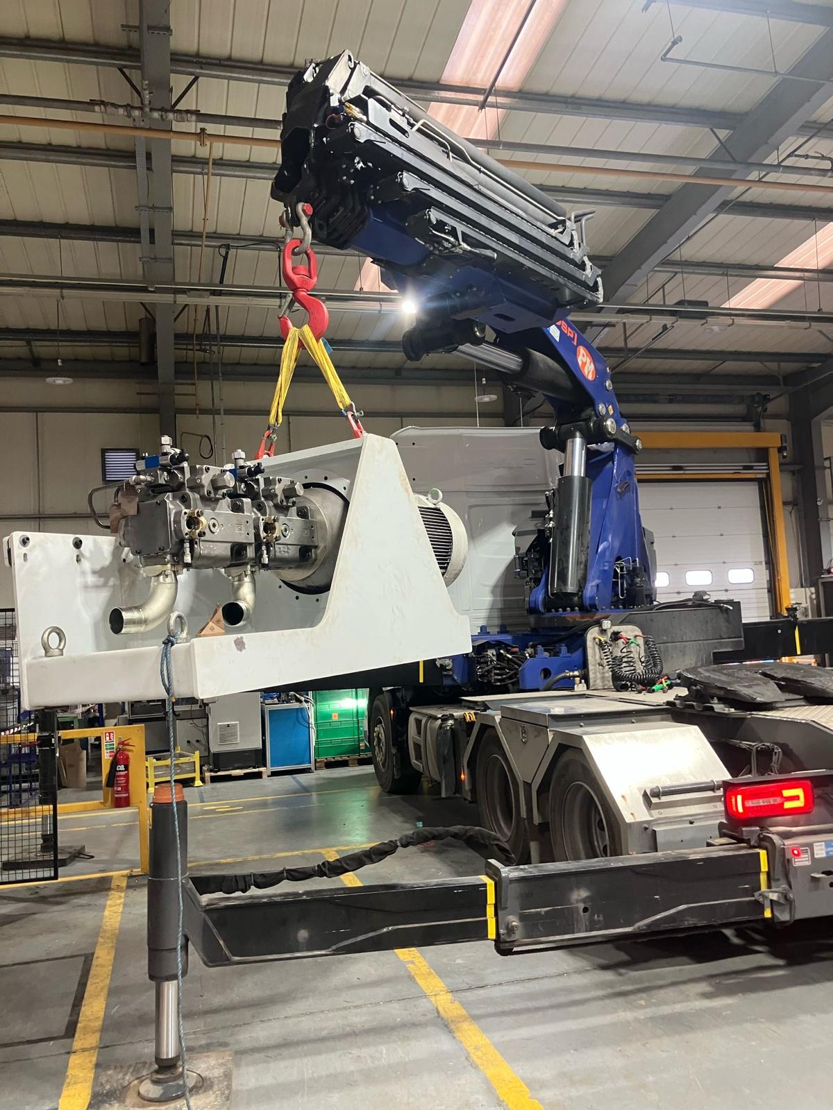 Truck mounted crane of Gerritsen Group lifting a machine within factory.
